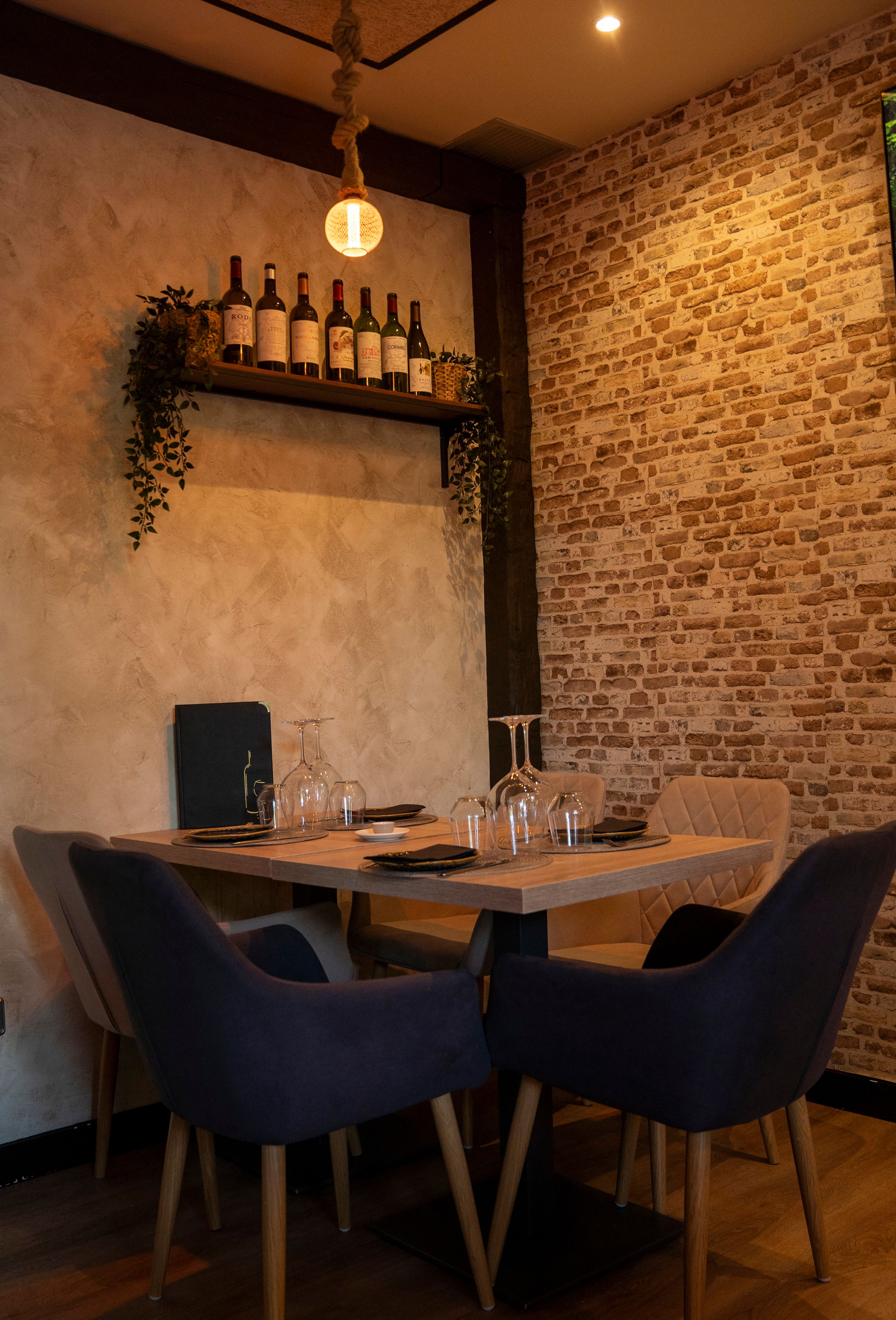 Mesa montada con copas y sillas junto a la pared de ladrillo en Vino y Verás, Las Tablas