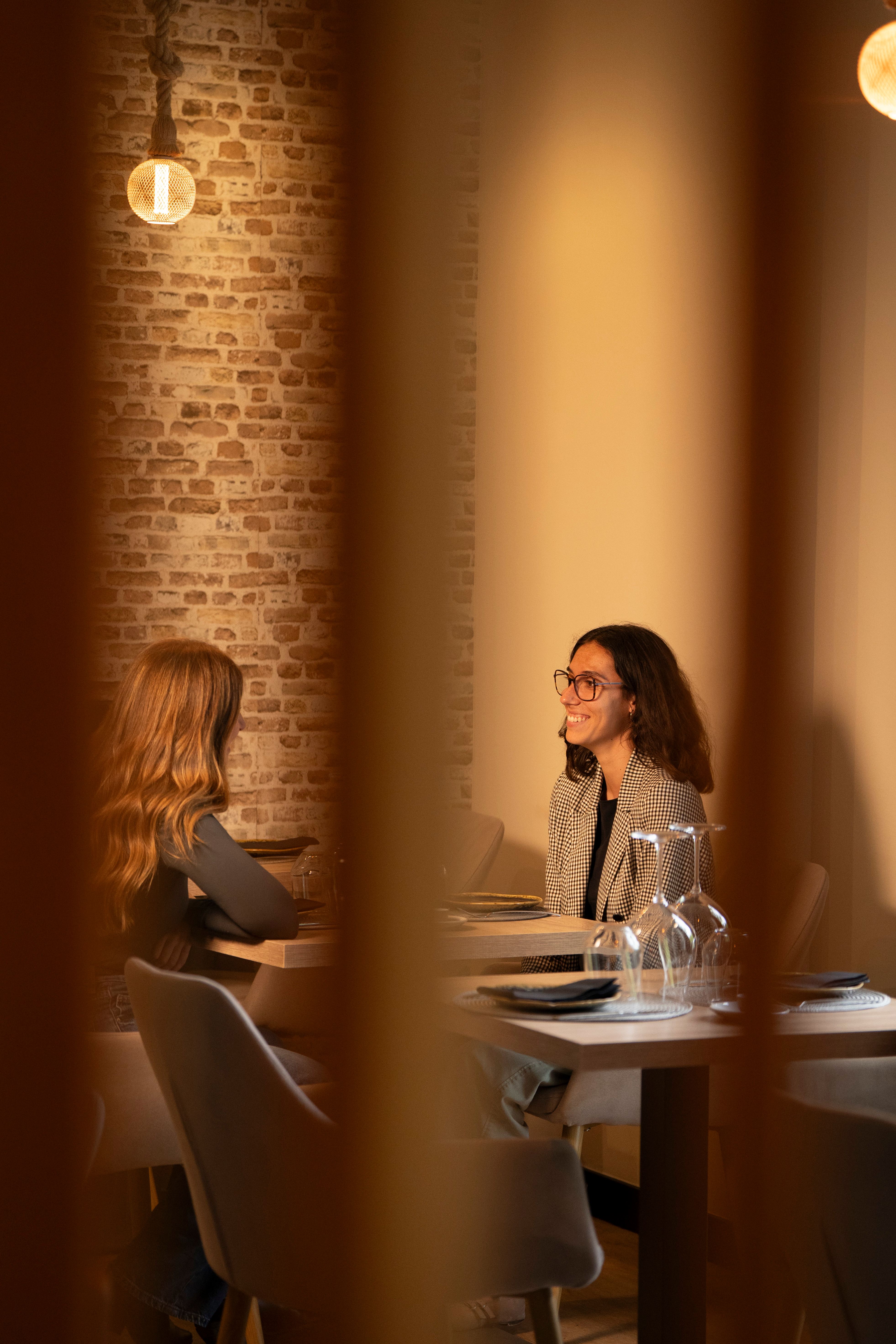 Dos comensales conversando en una mesa de Vino y Verás